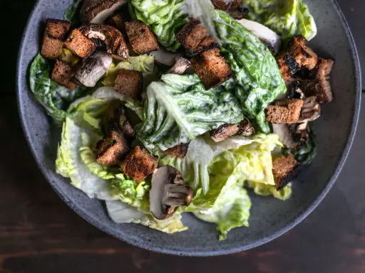 Herzhafter Caesar Salad mit knackigem Römersalat, gerösteten Croutons und Pilzen, übergossen mit cremiger Sauce.