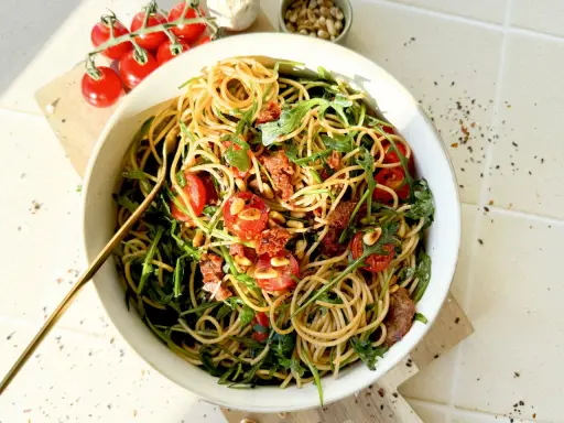 Mediterraner Salat mit getrockneten Tomaten und Rucola, garniert mit Pinienkernen. Ein köstliches Gericht, das nach Sommer schmeckt.