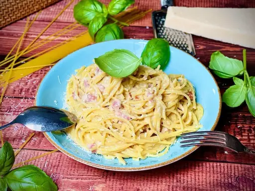 Herzhafte Spaghetti Carbonara mit Speck, garniert mit frischem Basilikum und Parmesan. Ein Klassiker, der immer schmeckt.