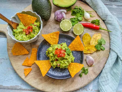 Frisches Guacamole-Rezept mit Avocados, Limetten, Chili und Koriander, serviert mit Tortilla-Chips.