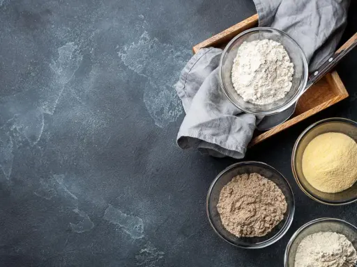 Schalen mit verschiedenen Mehlsorten, darunter auch was ist glutenfreies Mehl, auf dunklem Untergrund.