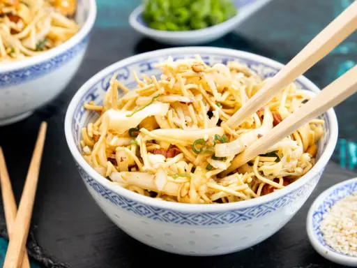 Ein Schüsselchen "friss dich dumm Salat" mit Nudeln, Gemüse und Erdnüssen, bereit zum Genießen mit Stäbchen.