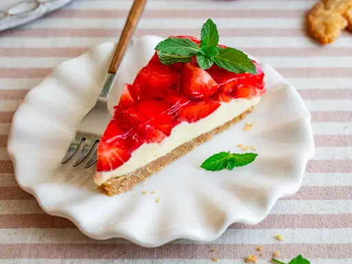Ein Stück Erdbeerkuchen mit Frischkäsefüllung und glasierten Erdbeeren, garniert mit Minze. Perfekt für einen 5 min kuchen ohne backen.