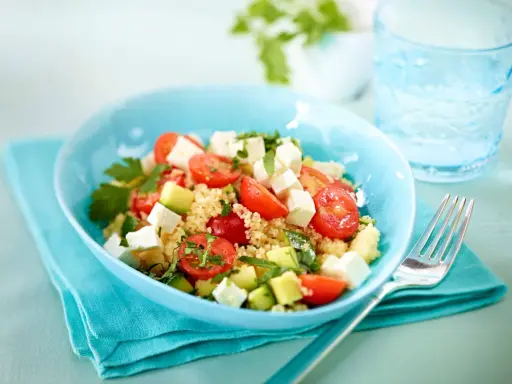 Erfrischender Couscous Salat mit Feta, Tomaten und Gurke in einer blauen Schüssel, bereit zum Genießen.