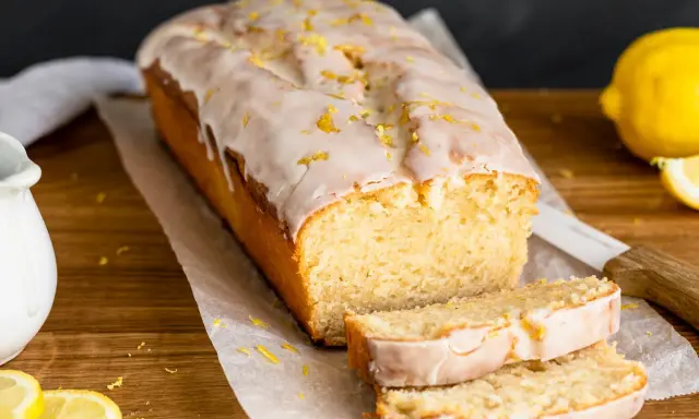 Saftiger veganer Zitronenkuchen mit Zuckerguss und Zitronenschale bestreut. Ein köstlicher Genuss!