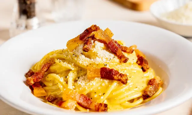 Spaghetti Carbonara mit knuspriger Pancetta, cremigem Ei und Käse bestreut. Ein Klassiker der italienischen Küche.