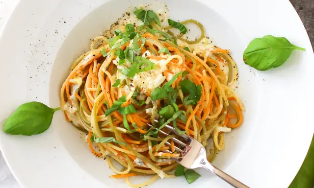 Bunte Spaghetti mit cremiger Gorgonzola-Sauce und frischem Basilikum, garniert mit Pfeffer. Ein Genuss für Augen und Gaumen.