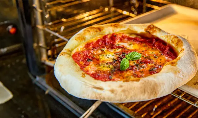 Eine köstliche Pizza mit geschmolzenem Käse und frischem Basilikum wird im Backofen gebacken.