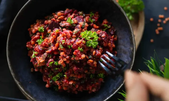 Ein köstlicher rote Linsen Salat mit Roter Bete und frischer Petersilie, serviert in einer dunklen Schüssel.