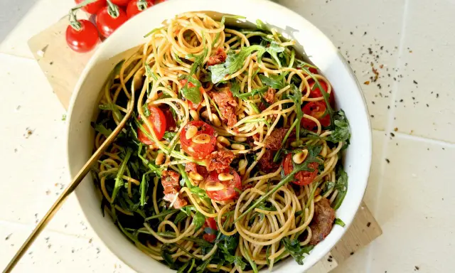 Mediterraner Salat mit getrockneten Tomaten und Rucola, garniert mit Pinienkernen. Ein köstliches Gericht, das nach Sommer schmeckt.