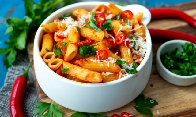 Eine Schüssel Penne all'Arrabbiata, garniert mit frischer Petersilie und Chilischeiben.