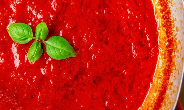 Frische, leuchtend rote italienische Tomatensauce mit Basilikumblättern, bereit für Pasta.