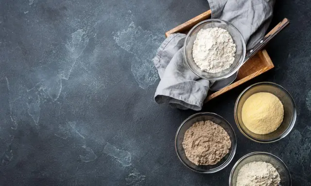 Schalen mit verschiedenen Mehlsorten, darunter auch was ist glutenfreies Mehl, auf dunklem Untergrund.