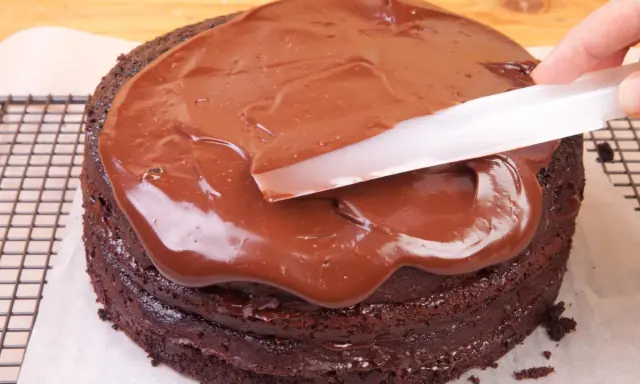 Schokoladenkuchen wird mit glatter, glänzender Ganache überzogen. Was ist eine Ganache? Eine köstliche Mischung aus Schokolade und Sahne.