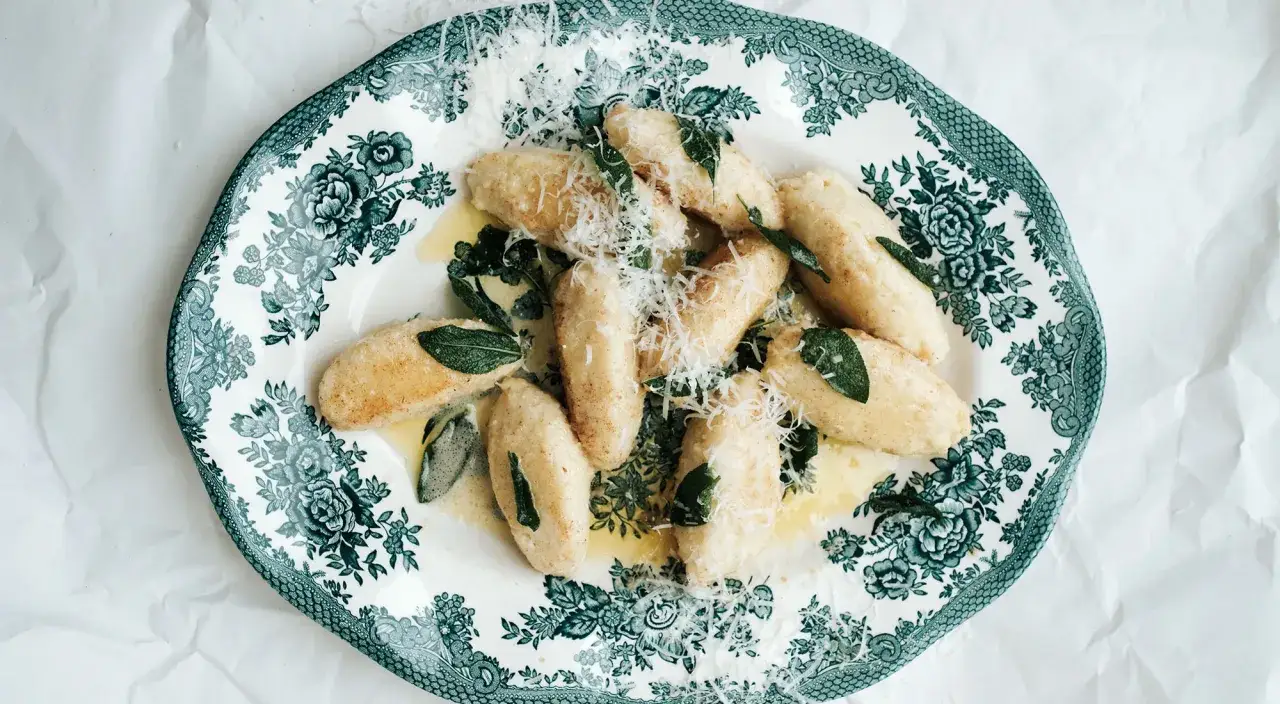 Leckeres Gnudi Rezept: Ricotta-Gnocchi mit Salbeibutter und Parmesan auf einem Vintage-Teller.