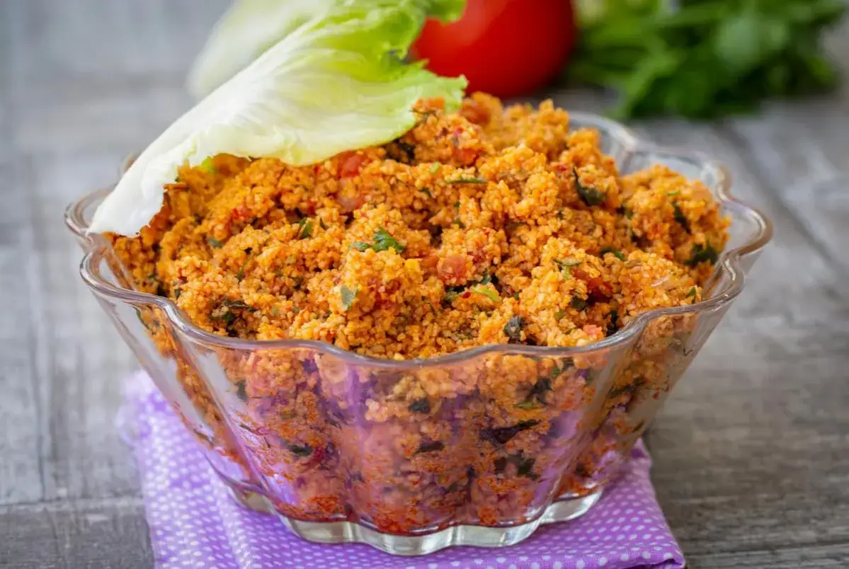 Ein k&ouml;stlicher Couscous-Salat mit Tomaten und Kr&auml;utern, garniert mit einem Salatblatt.