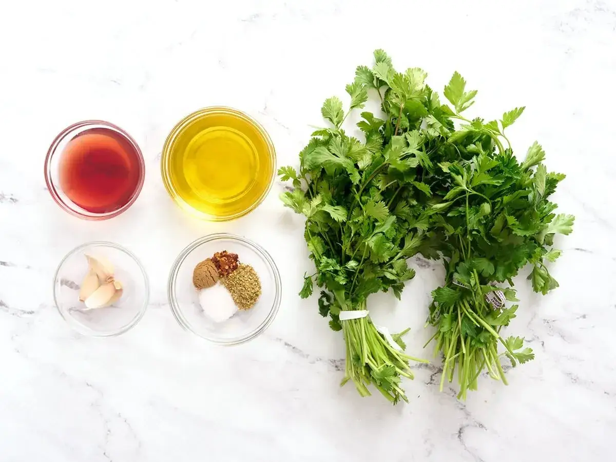 Zutaten f&uuml;r ein Chimichurri Rezept: frische Kr&auml;uter, &Ouml;l, Essig, Knoblauch und Gew&uuml;rze.