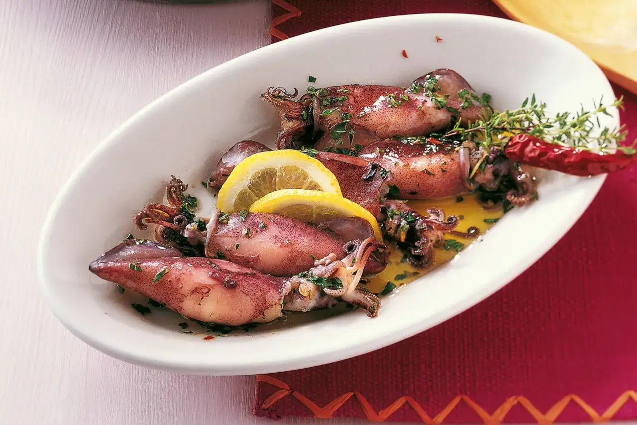 Fertig zubereitete Tintenfischtuben im Ofen, garniert mit Zitrone, Kr&auml;utern und Chili. Die Frage 