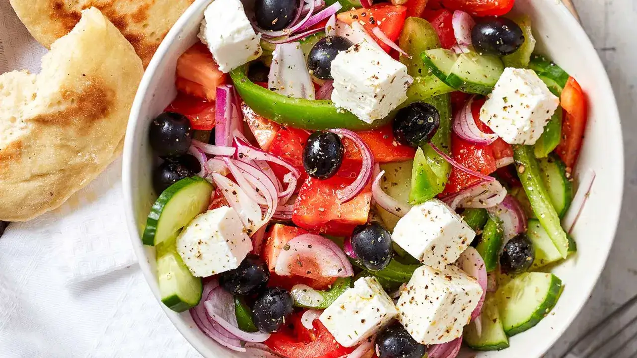 Frischer griechischer Salat mit Tomaten, Gurken, Oliven, Feta und Zwiebeln, serviert mit Pitabrot.