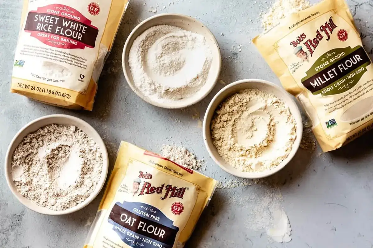 Verschiedene glutenfreie Mehlsorten wie Reis-, Hafer- und Hirsemehl liegen in Schalen und S&auml;cken bereit.
