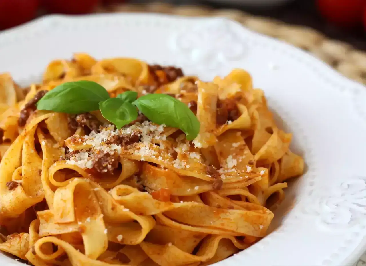 Breite Bandnudeln mit herzhaftem Ragu, garniert mit frischem Basilikum und Parmesan. Ein Genuss f&uuml;r Pasta-Liebhaber.