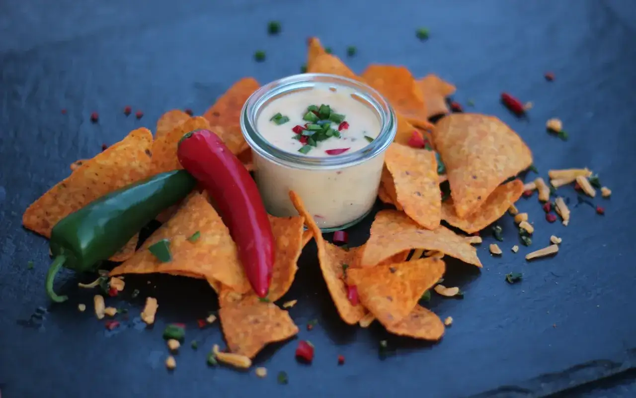 Nachos mit einer cremigen Chili Cheese Sauce, garniert mit frischen Chilis und Gewürzen.