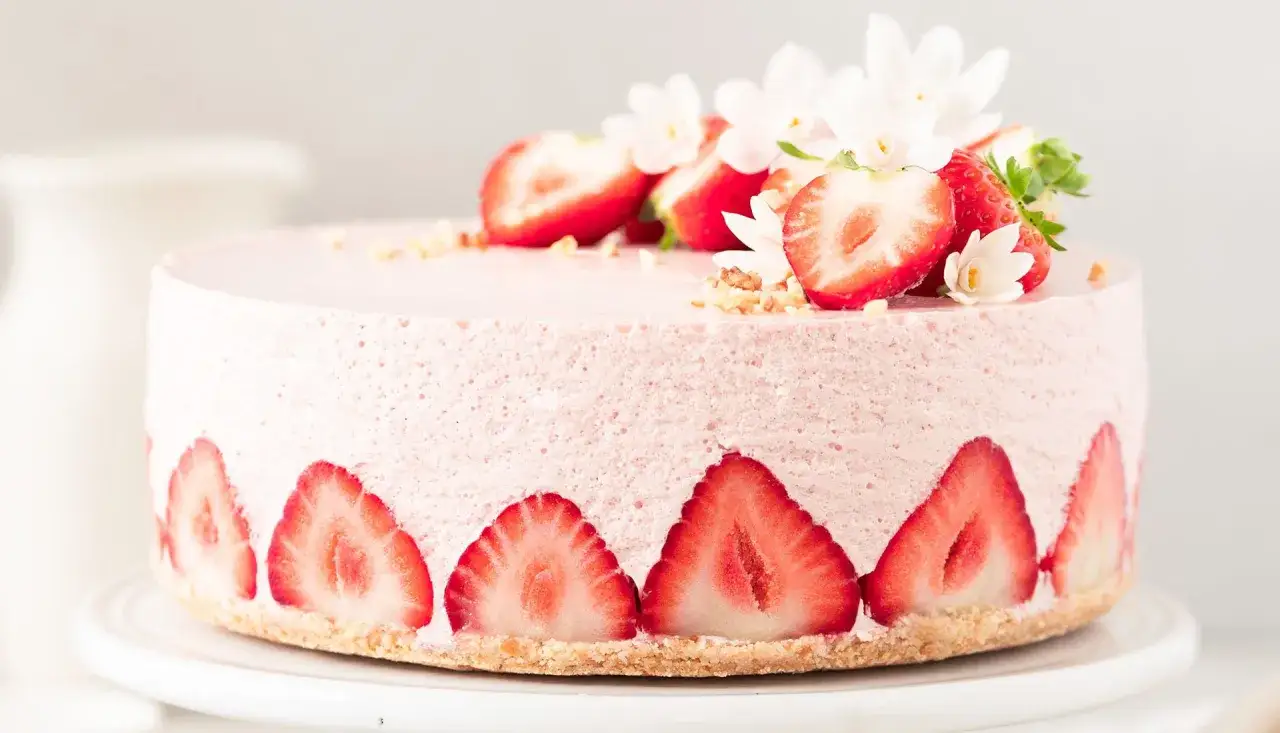 Ein zarter Erdbeer-Cheesecake, dekoriert mit frischen Erdbeerscheiben und Bl&uuml;ten. Perfekt f&uuml;r Ihr n&auml;chstes erdbeer cheesecake rezept.