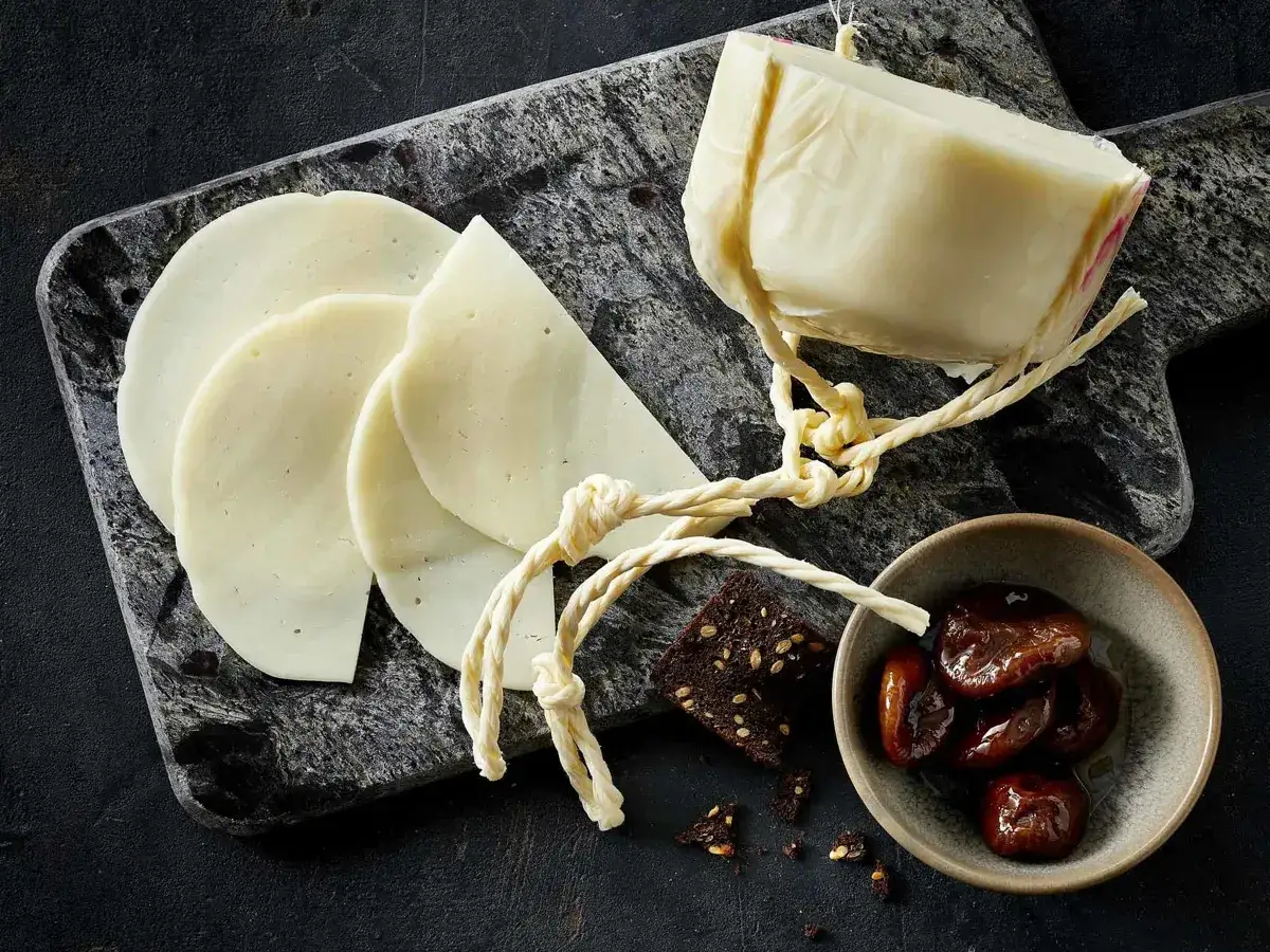 Ein St&uuml;ck K&auml;se, geschnitten und als provolone alternative pr&auml;sentiert, mit Feigen und Brot.