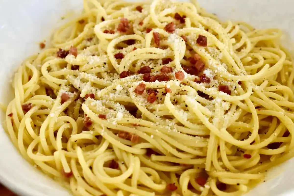 Eine Portion Spaghetti Carbonara, garniert mit ger&auml;uchertem Pancetta und frisch geriebenem Parmesan.