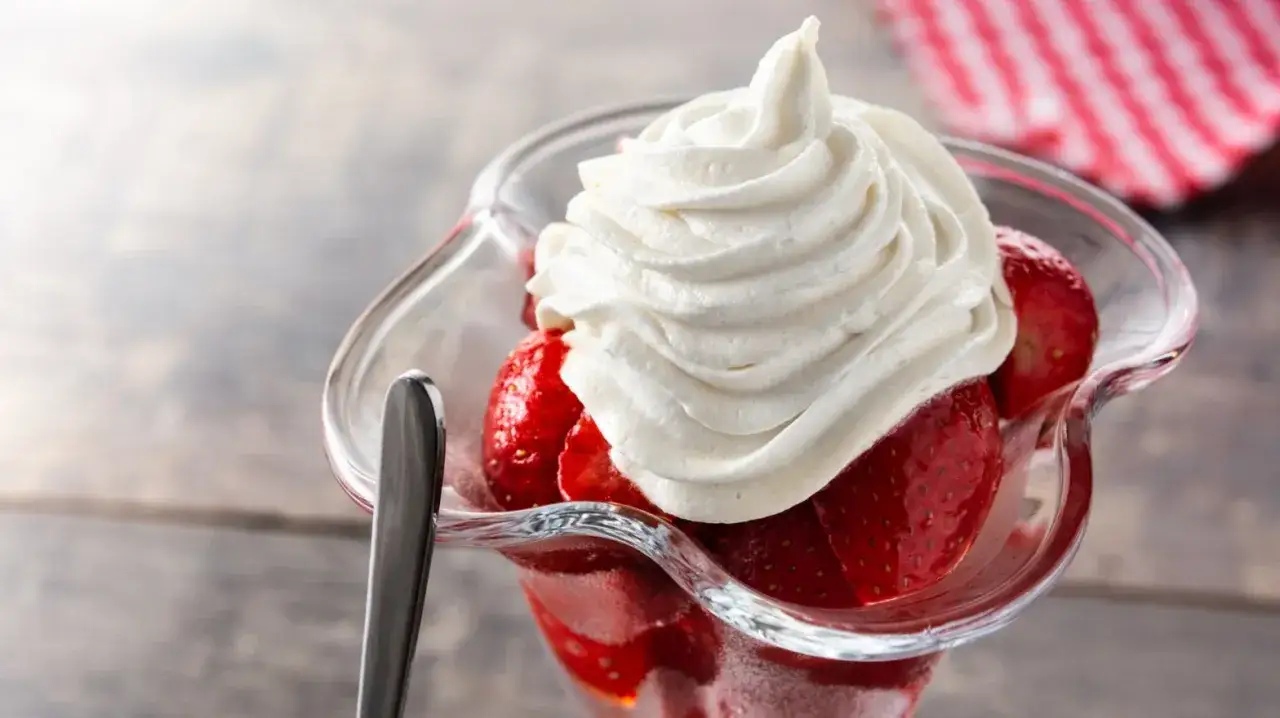 Frische Erdbeeren mit selbstgemachter Sahne in einer Glasschale, ein k&ouml;stlicher Genuss.