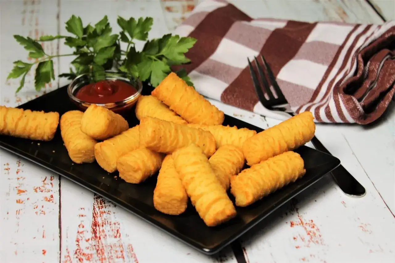 Goldbraune Kroketten, frisch zubereitet, liegen auf einem schwarzen Teller mit Ketchup und Petersilie. Perfekt zum kroketten selber machen!