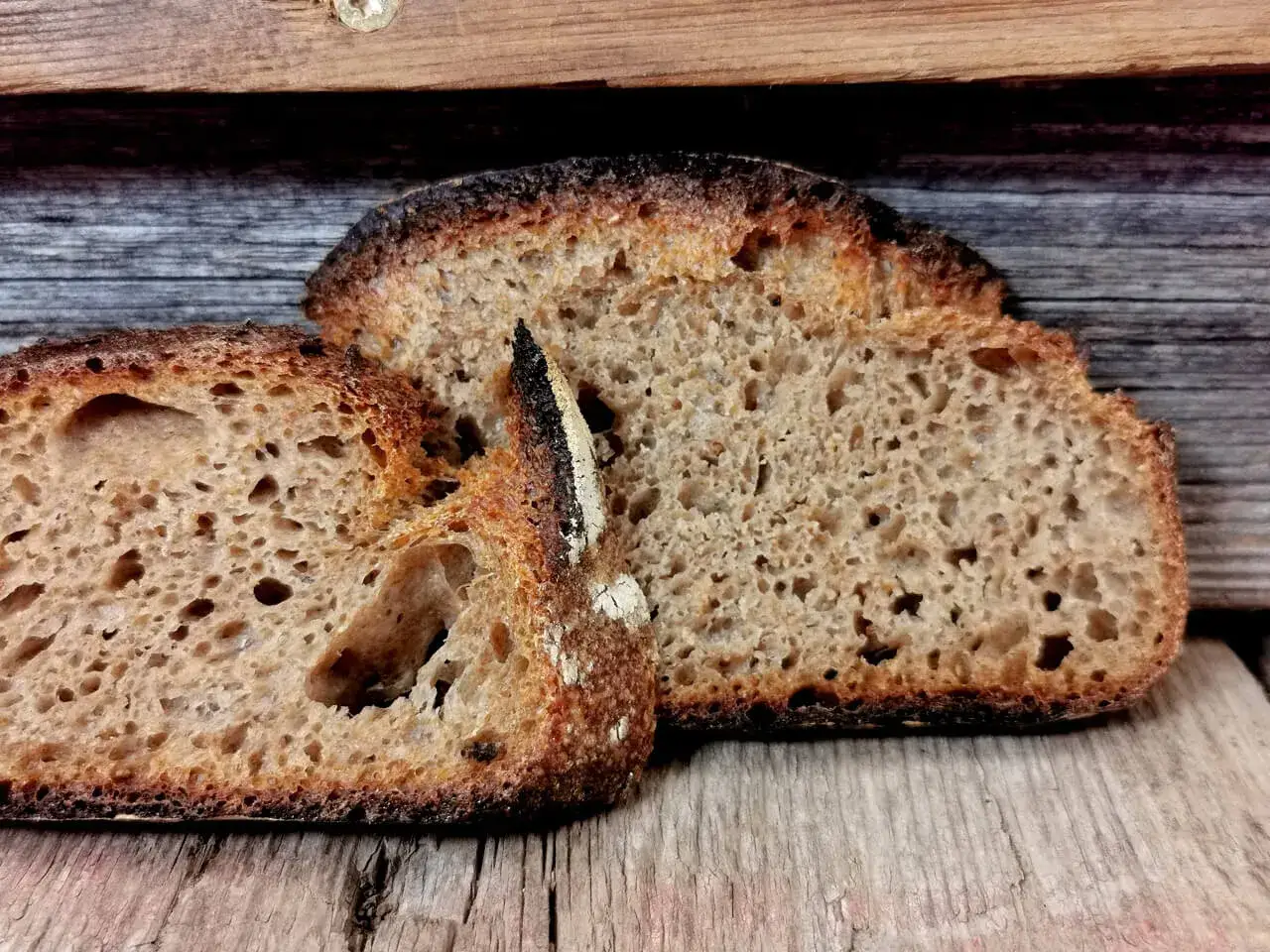 Zwei Scheiben rustikales Brot, perfekt zum Backen mit Vollkornmehl. Die Kruste ist knusprig, das Innere luftig.