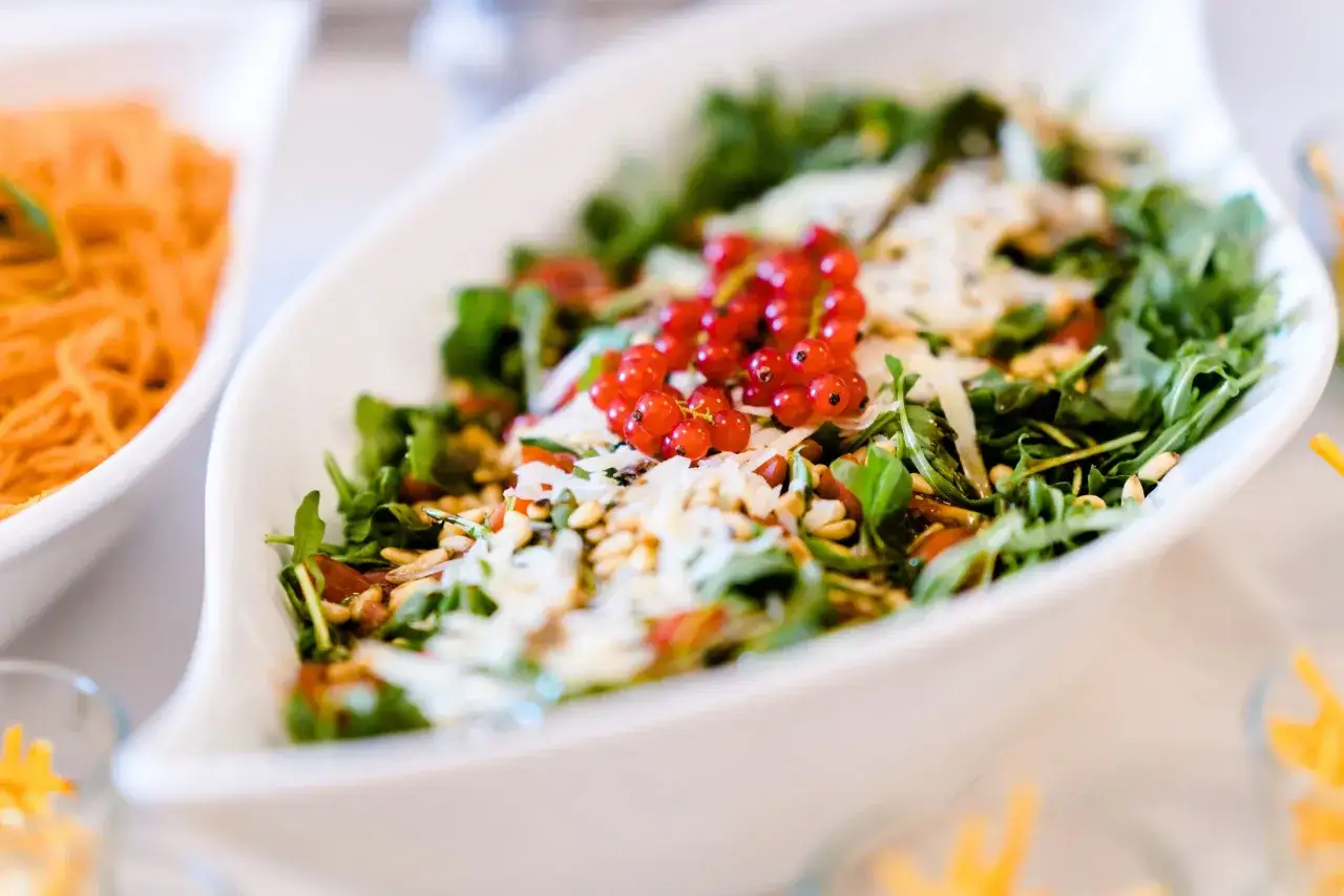 Ein frischer Rucola Salat mit roten Johannisbeeren, Pinienkernen und Parmesan.