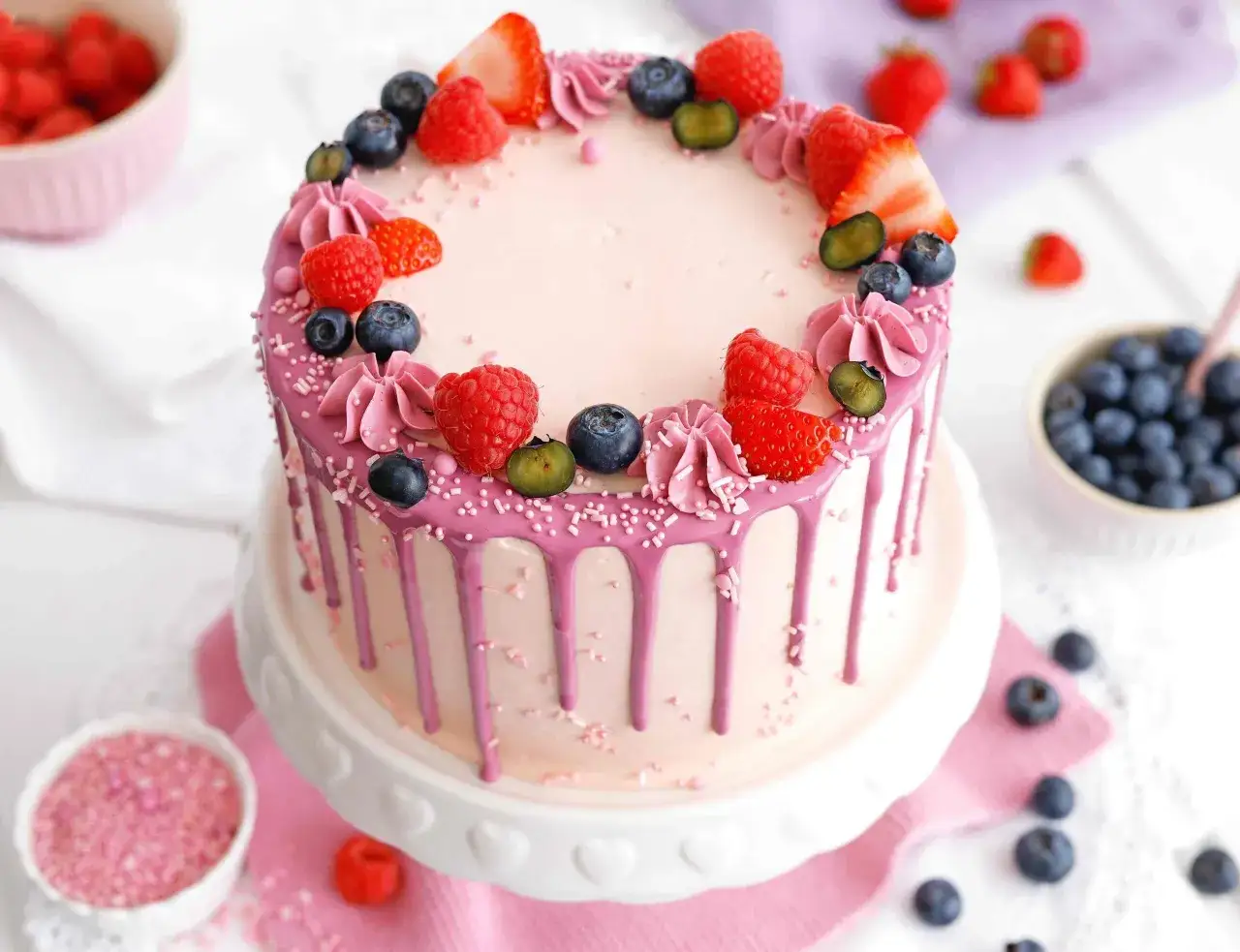 Ein rosa getropfter Kuchen mit Beeren und Sahnetupfern. Tolle torten verzieren ideen für jeden Anlass!