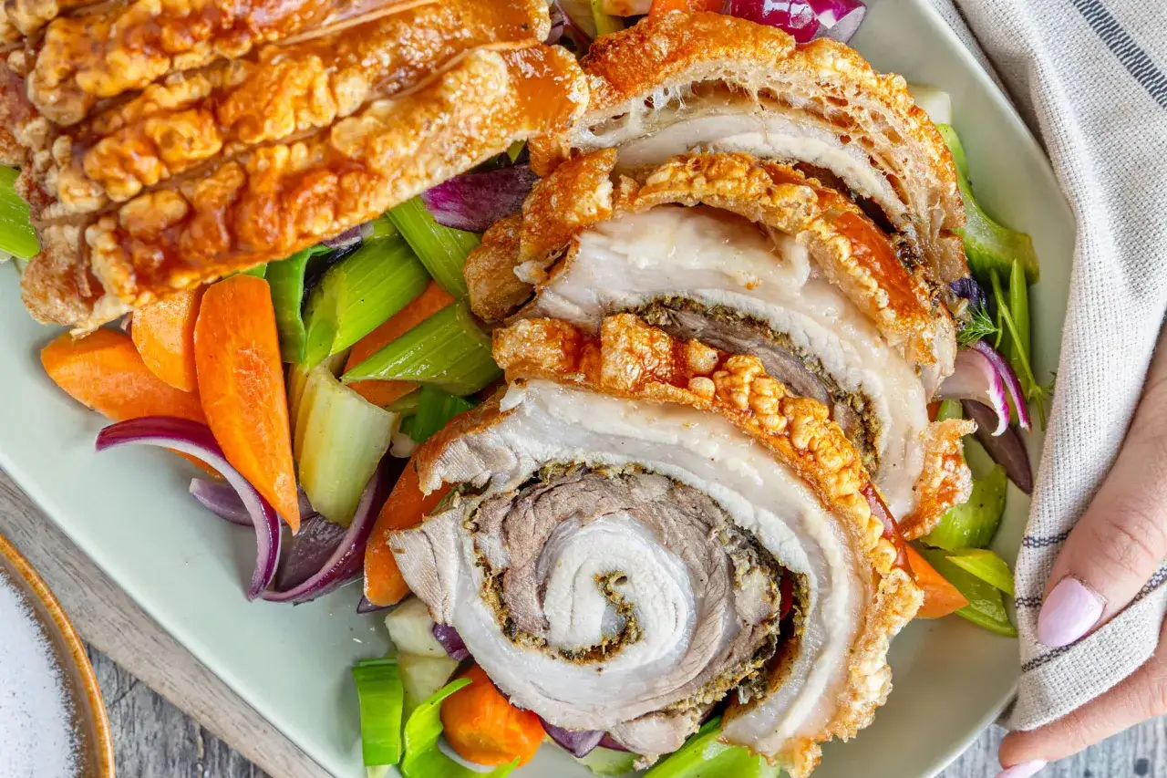 Knuspriges, gerolltes Schweinefleisch mit Kr&auml;utern, serviert mit Karotten, Sellerie und Zwiebeln. Das ist Porchetta, ein italienischer Klassiker.