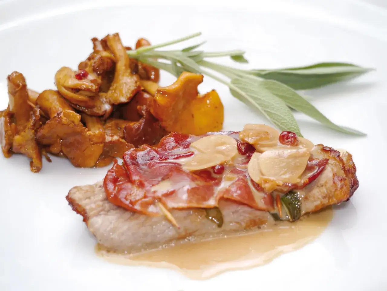Saltimbocca alla Romana: zarte Kalbsschnitzel mit Salbei und Prosciutto in einer cremigen Sauce, serviert mit gebratenen Pfifferlingen.