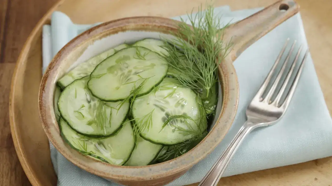 Frischer Gurkensalat mit Dill, ein leichtes Rezept f&uuml;r hei&szlig;e Tage. Serviert in einer rustikalen Schale mit einer Gabel.
