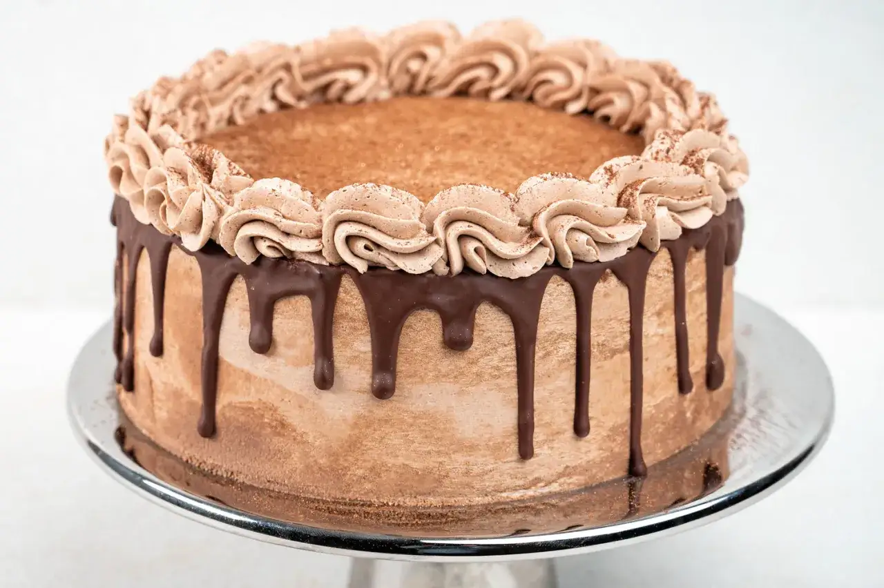 Schokoladenkuchen mit Cookie Dough-Geschmack, verziert mit Schokoladenglasur und Sahnetuffs.
