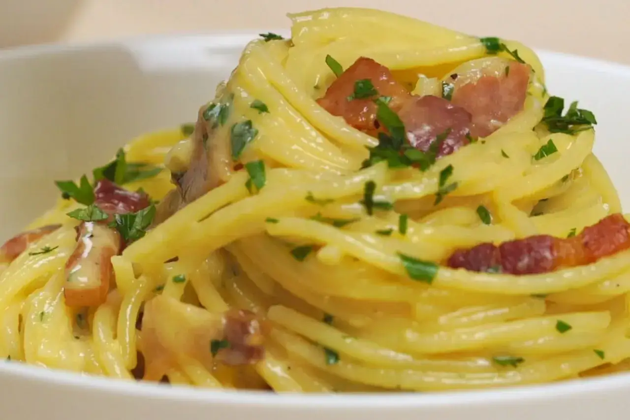 Ein Teller cremiger Spaghetti Carbonara, garniert mit Speck und Petersilie. Perfekt f&uuml;r ein schnelles und einfaches Spaghetti Carbonara Rezept.
