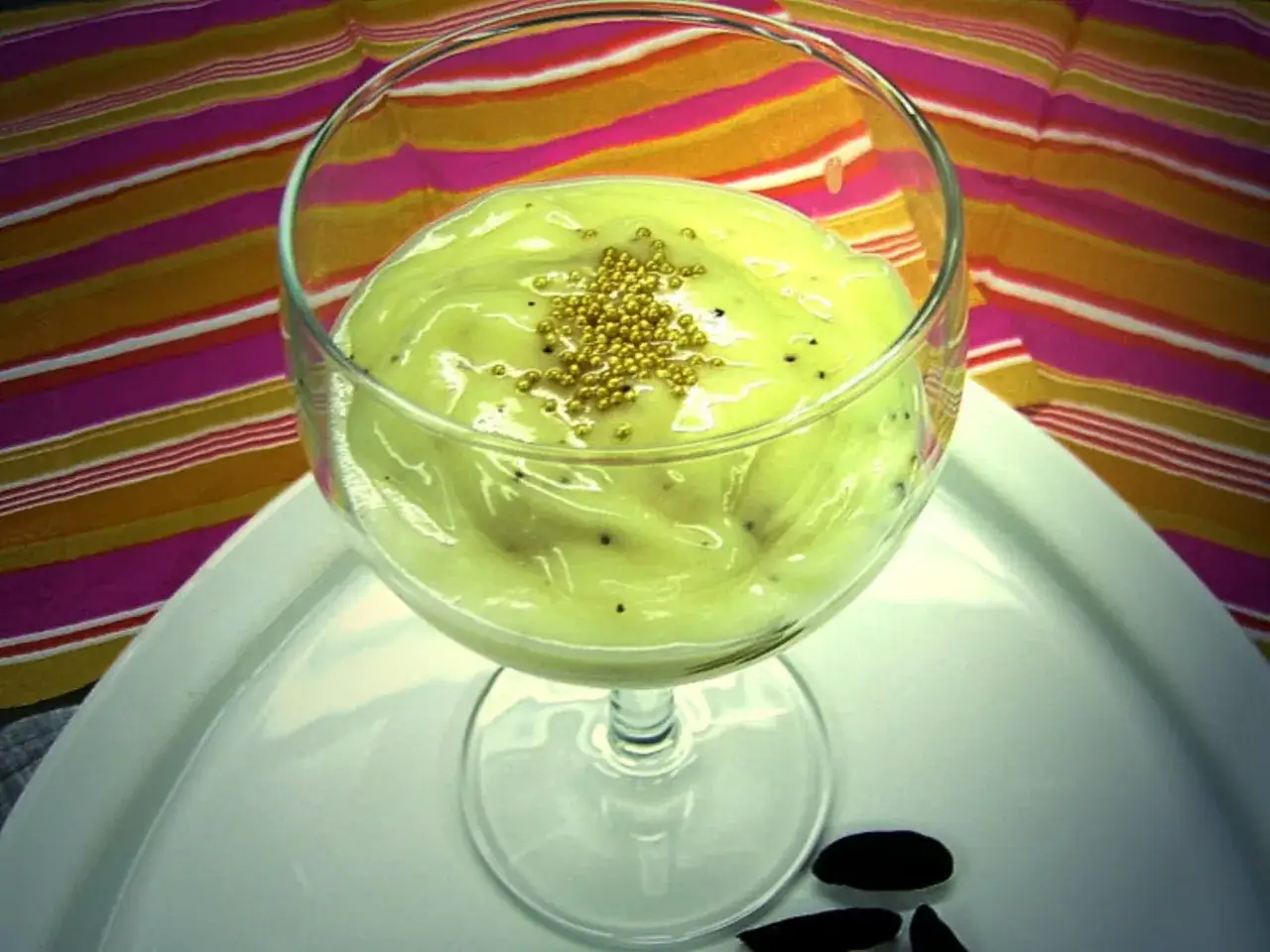 Cremiges Dessert im Glas, garniert mit goldenen Perlen. Der Geschmack erinnert an Vanille und Mandeln, wie bei der Tonkabohne.
