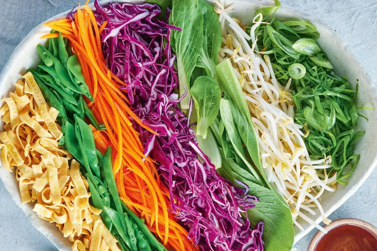 Bunte Zutaten für einen leckeren Yum Yum Salat: Nudeln, Zuckerschoten, Karottenstreifen, Rotkohl, Pak Choi, Sojasprossen und Frühlingszwiebeln.