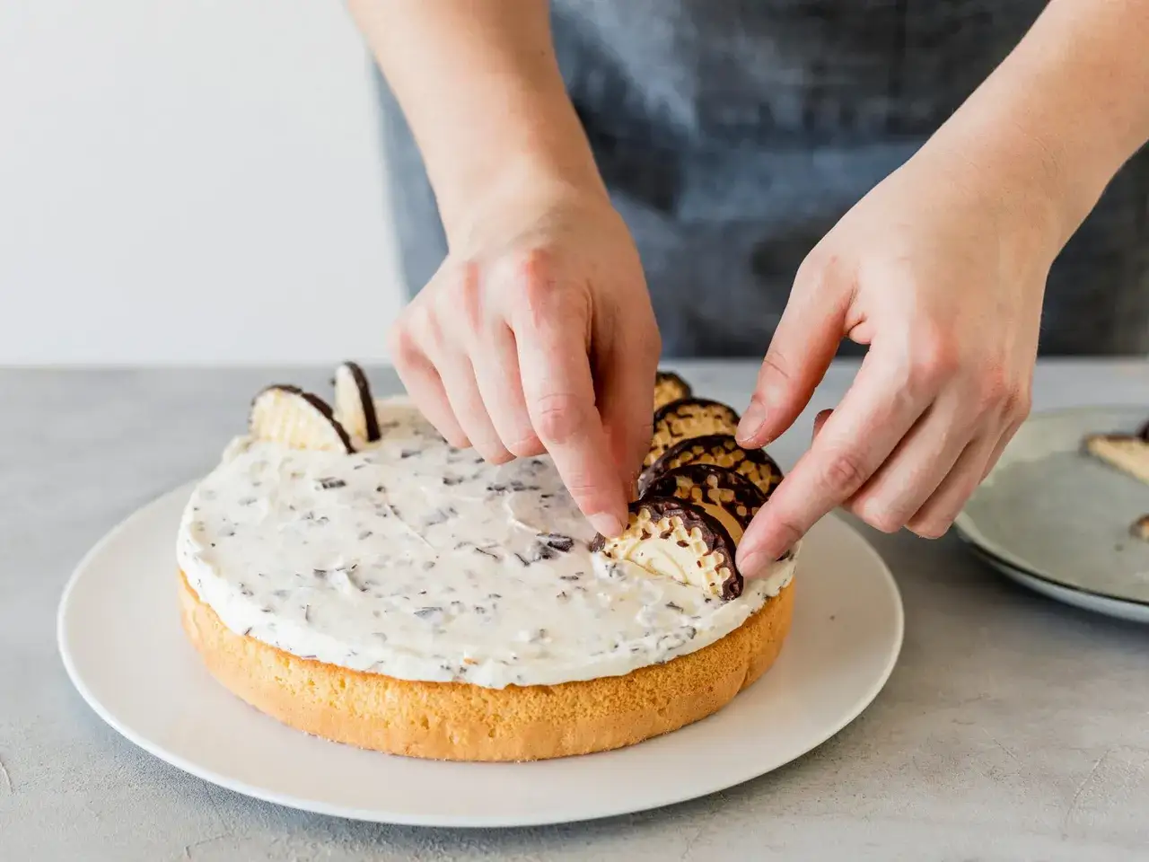 Hände verzieren eine Mohrenkopftorte mit Schokoladenwaffeln. Ein leckeres Rezept für den Genuss!