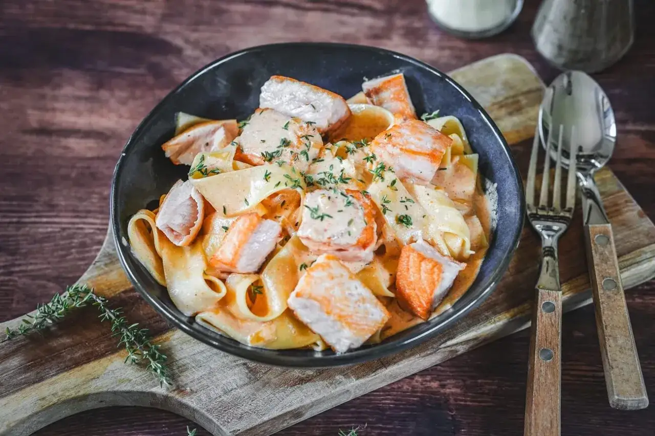 Breite Bandnudeln mit saftigen Lachs-St&uuml;cken in cremiger Lachs Sahne Sauce, garniert mit frischen Kr&auml;utern.
