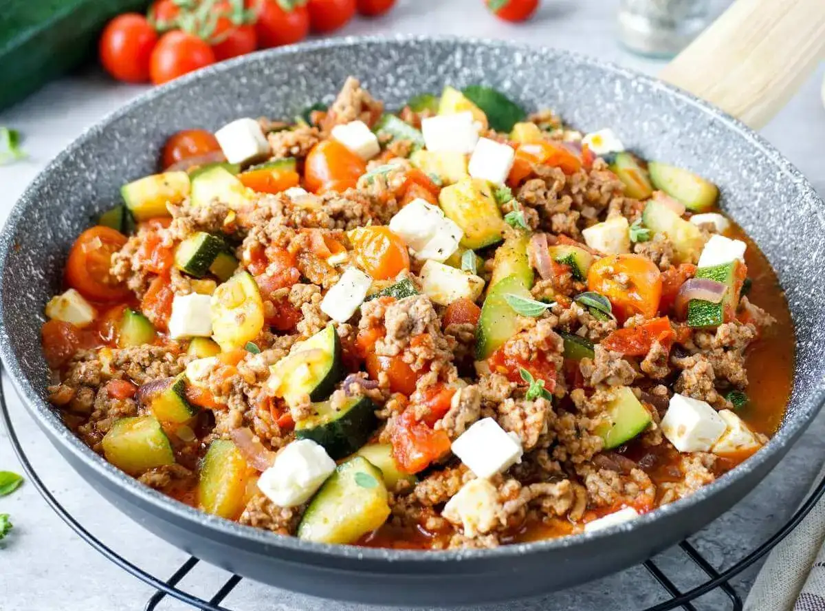 Herzhaftes Gericht aus zucchini mit hackfleisch, Tomaten und Feta in einer Pfanne.