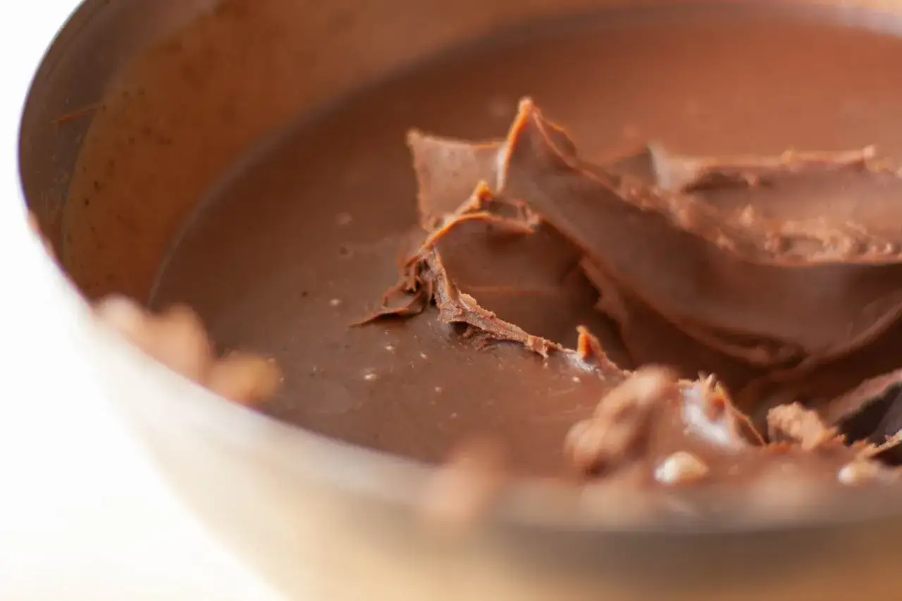 Eine Sch&uuml;ssel mit glatter, gl&auml;nzender Schokoladenmasse, die zeigt, was eine Ganache ist. Die Textur ist cremig und reichhaltig.