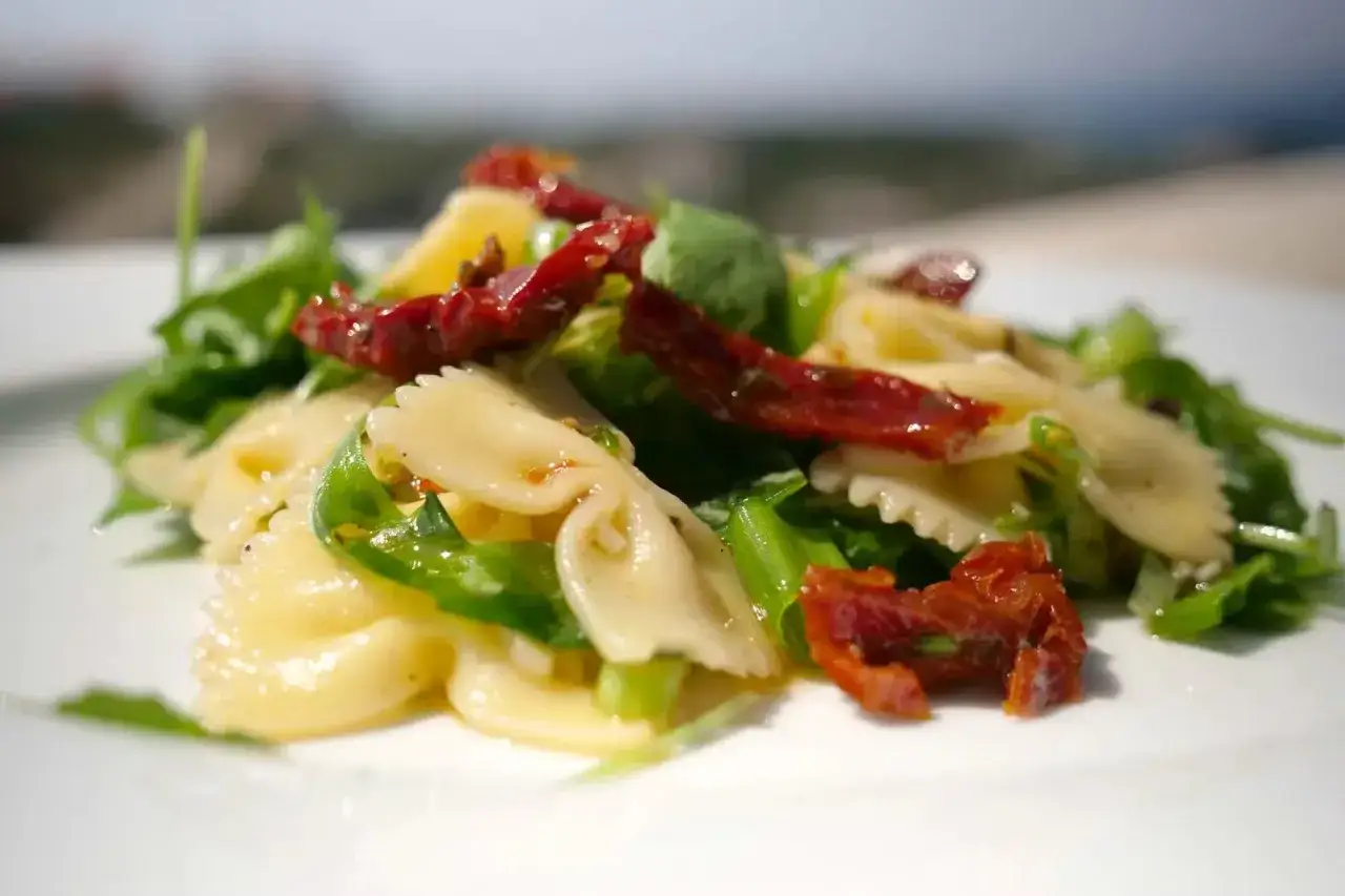 Leckerer nudelsalat ohne mayo mit Farfalle, Rucola und sonnengetrockneten Tomaten. Ein leichter Genuss f&uuml;r warme Tage.