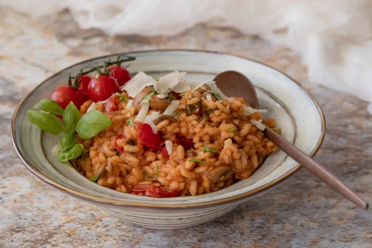 Ein cremiges Risotto mit Pilzen und Tomaten, garniert mit frischem Basilikum und Parmesan.