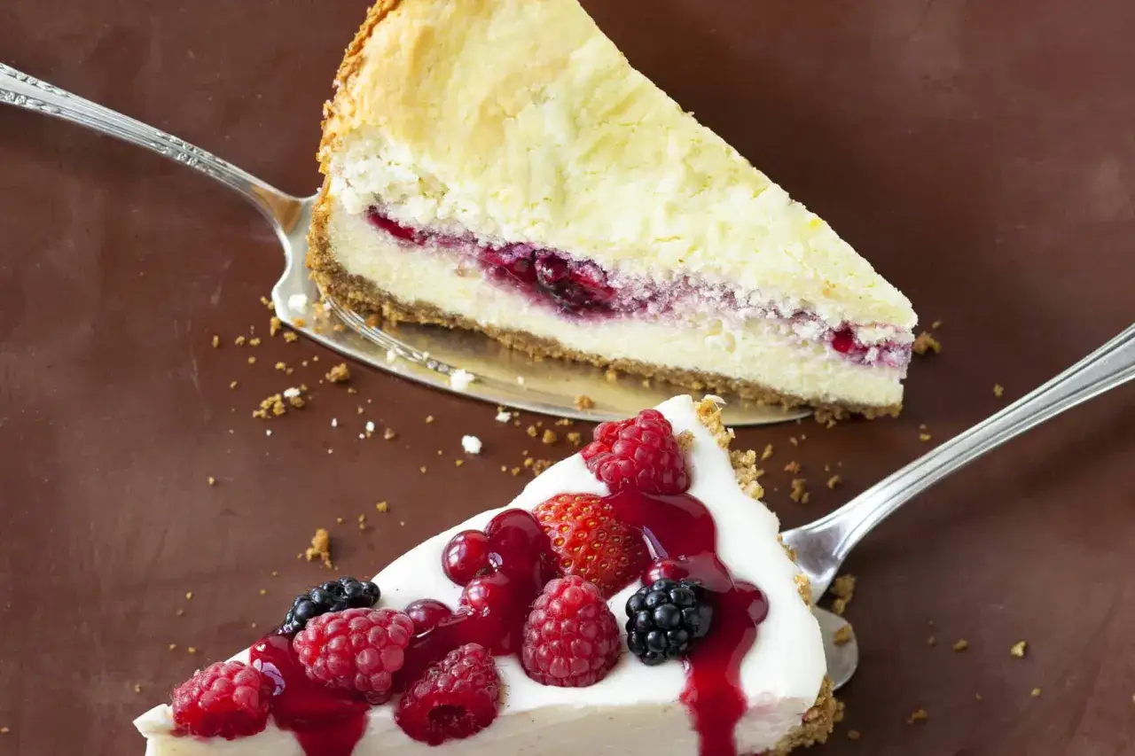 Zwei cremige K&auml;sekuchenst&uuml;cke, eines mit Beeren garniert, das andere mit roter Fruchtsauce. Ein k&ouml;stlicher Kuchen ohne Backen!