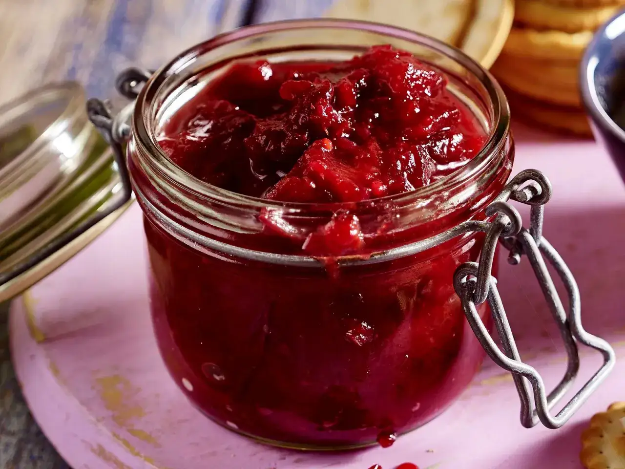 Ein Glas mit leuchtend rotem Zwetschgen-Chutney, bereit, zu Käse oder Gebäck genossen zu werden.