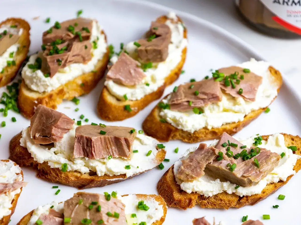 Geröstete Brotscheiben mit cremiger Ricotta und saftigen Thunfischstücken, garniert mit Schnittlauch. Ein Hauch von italienischer Thunfischcreme.